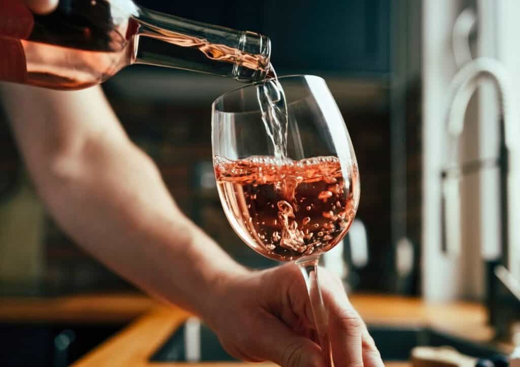 Man pouring rose wine into a glass.