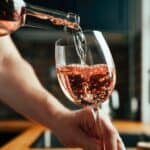 Man pouring rose wine into a glass.