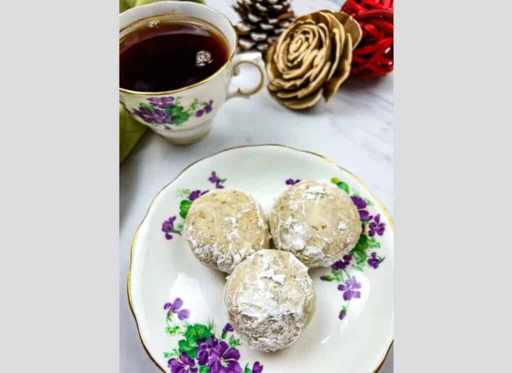 Three Pecan Butter Balls on a white plate with purple flower designs.