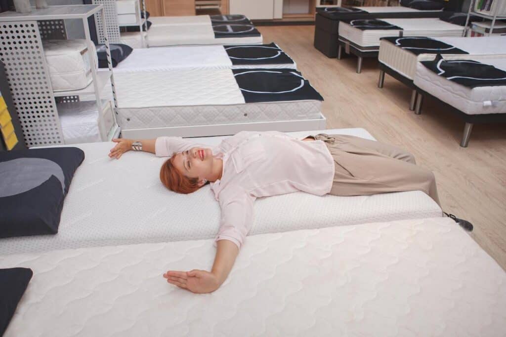 Young woman shopping at furniture store for a new mattress.