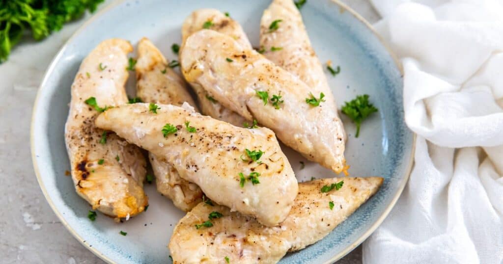 cooked naked chicken tenders on a blue plate.