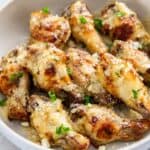 garlic parm wings in a white bowl topped with parsley