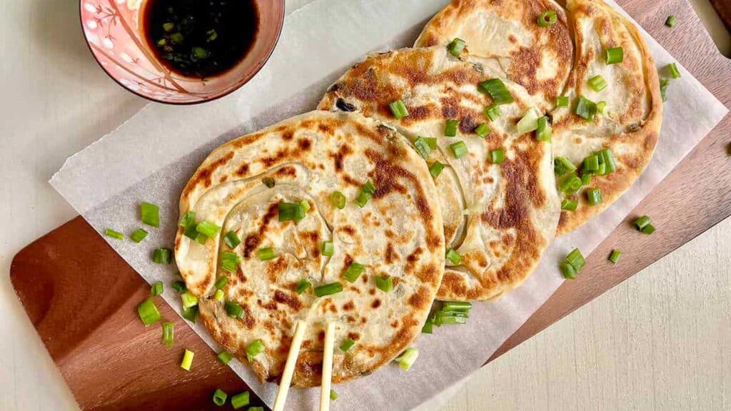 overhead shot of scallion pancakes with soy dipping sauce and chopsticks.