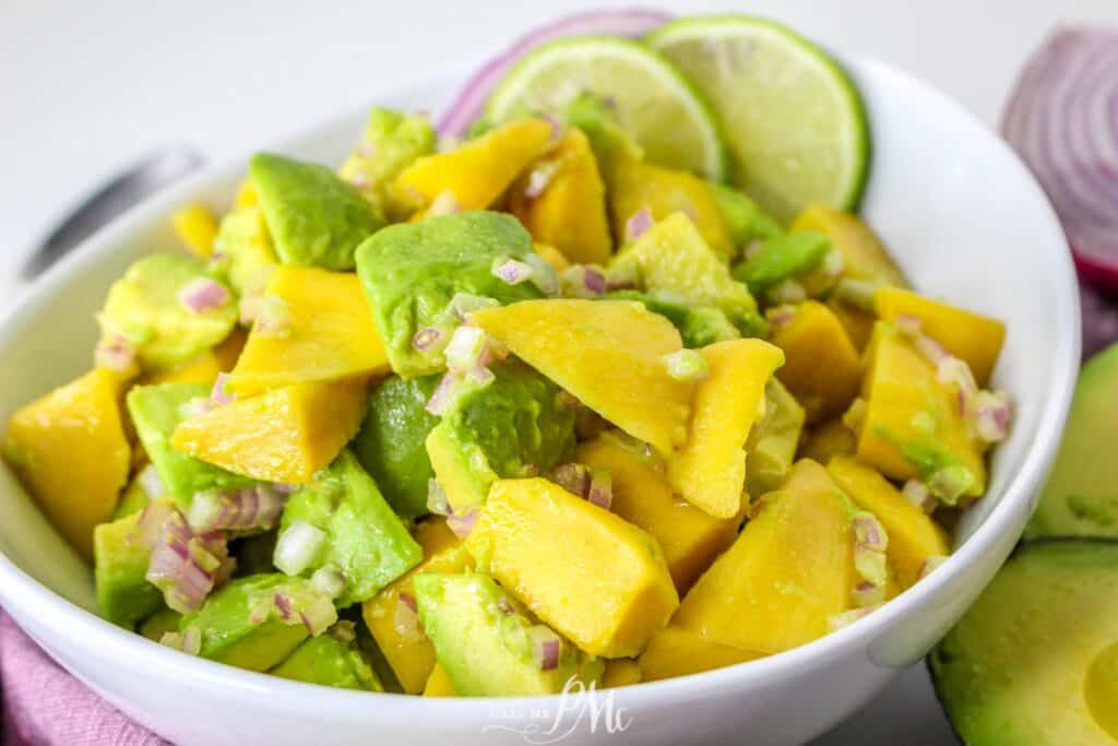 Avocado mango salad in white bowl.