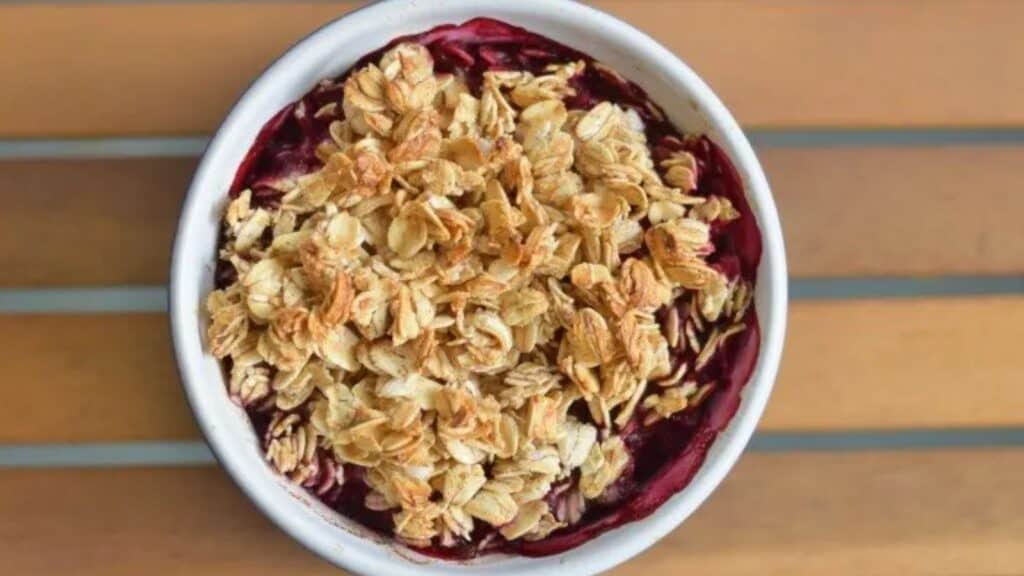 Image shows an overhead closeup shot of a Baked Cherry Oatmeal in a ramekin on a wooden table.