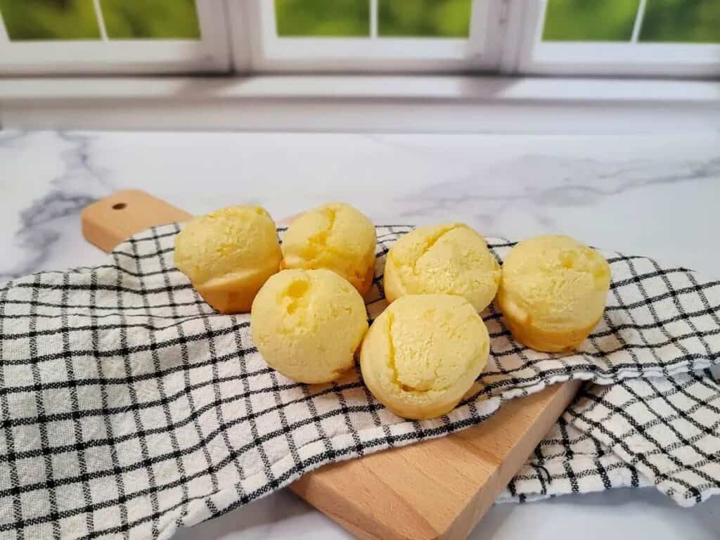 Brazilian cheese bread bites cooling on a kitchen counter.