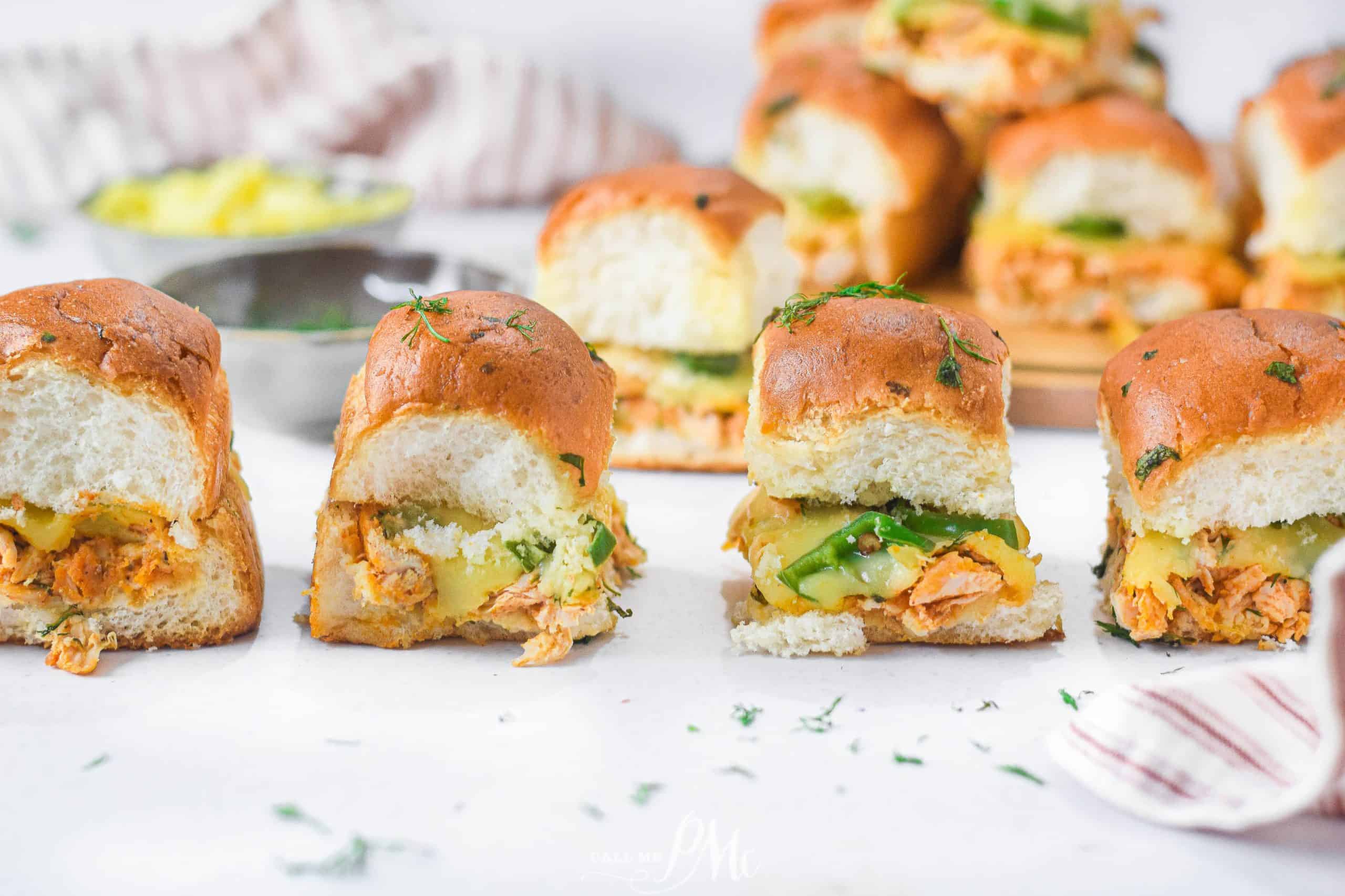 Small chicken sandwiches with cheese on a table.