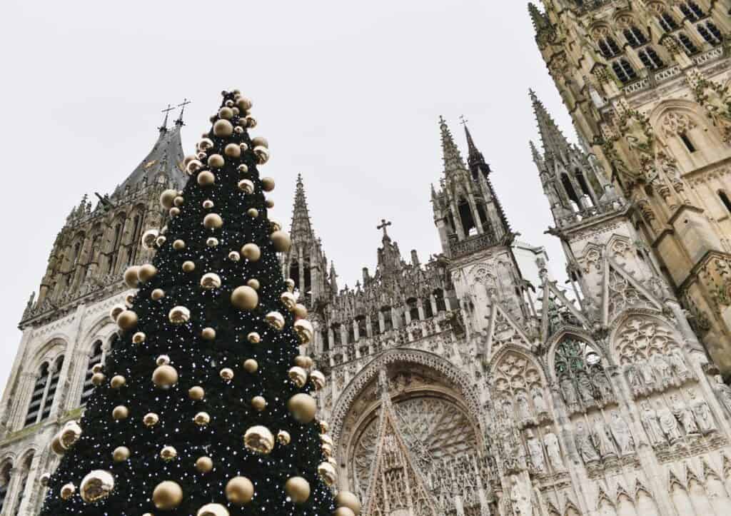 A decorated Christmas tree outside a Gothic cathedral in Rouen, France.