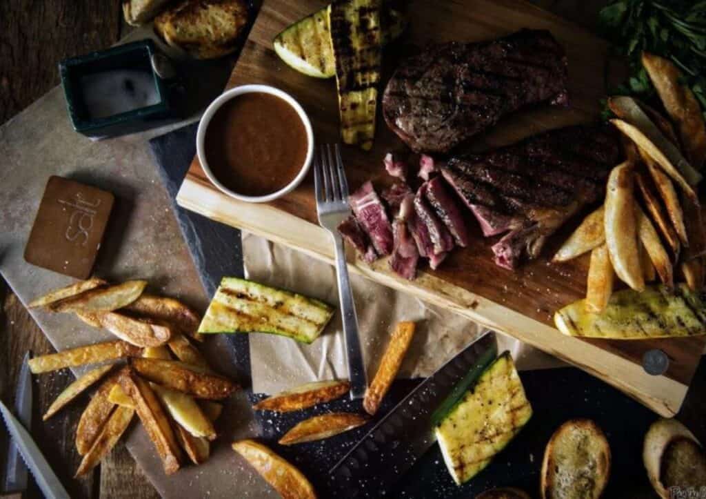 Overhead of steak sliced and grilled veg and potatoes.