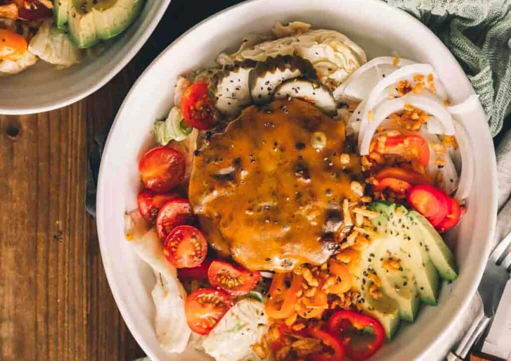 Overhead shot of cheeseburger atop a salad.