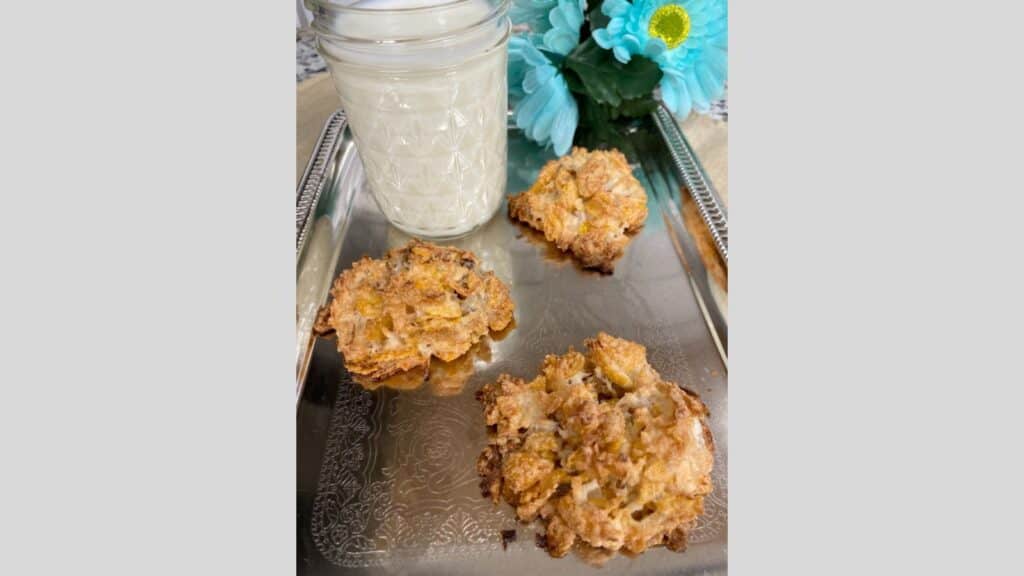 Three Corn Flake macaroons on silver platter with glass of milk in background.
