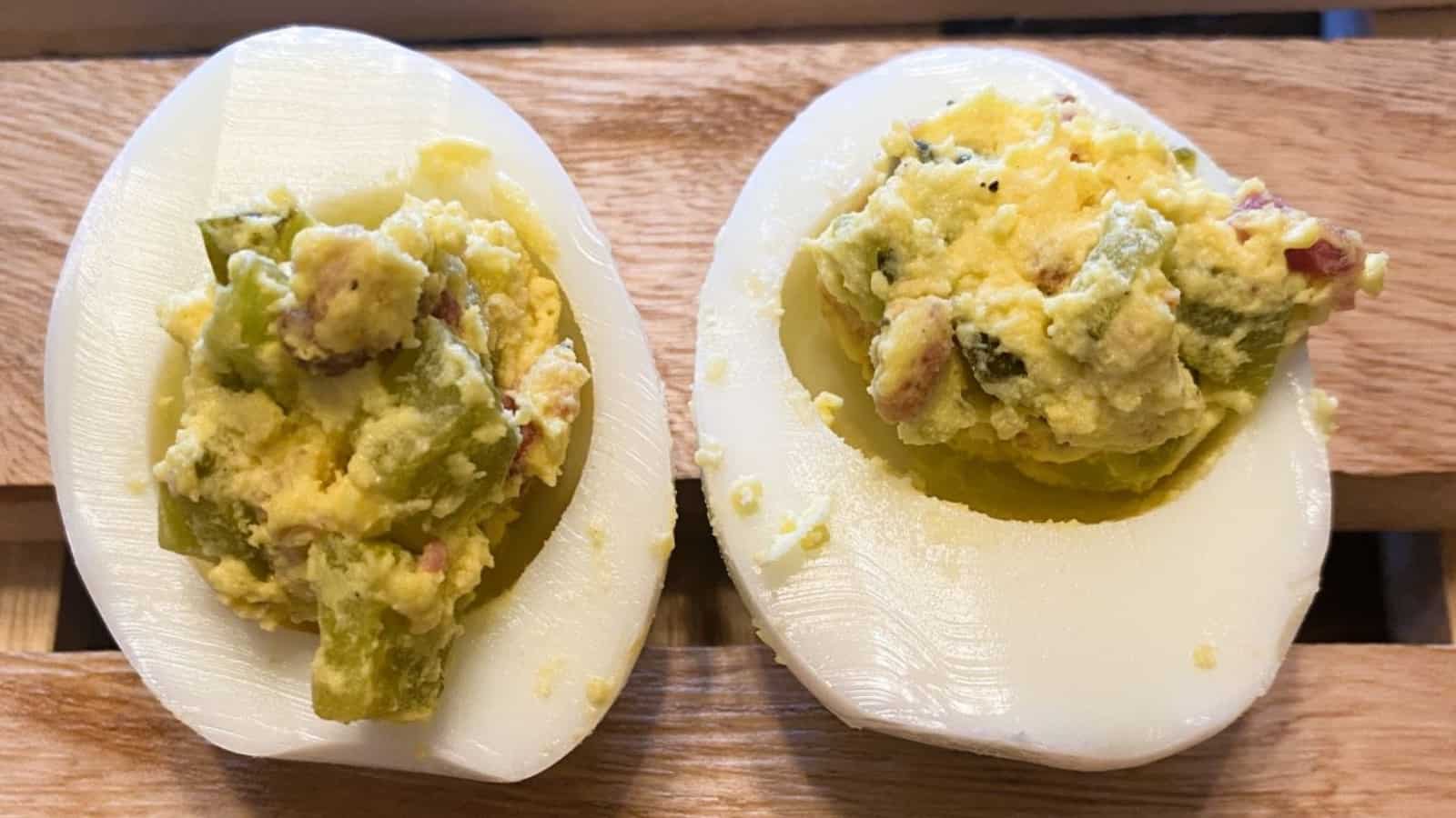 Two deviled eggs on a wooden table.