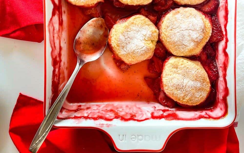Strawberry cobbler in a 9x9 pan with some taken out of it. 
