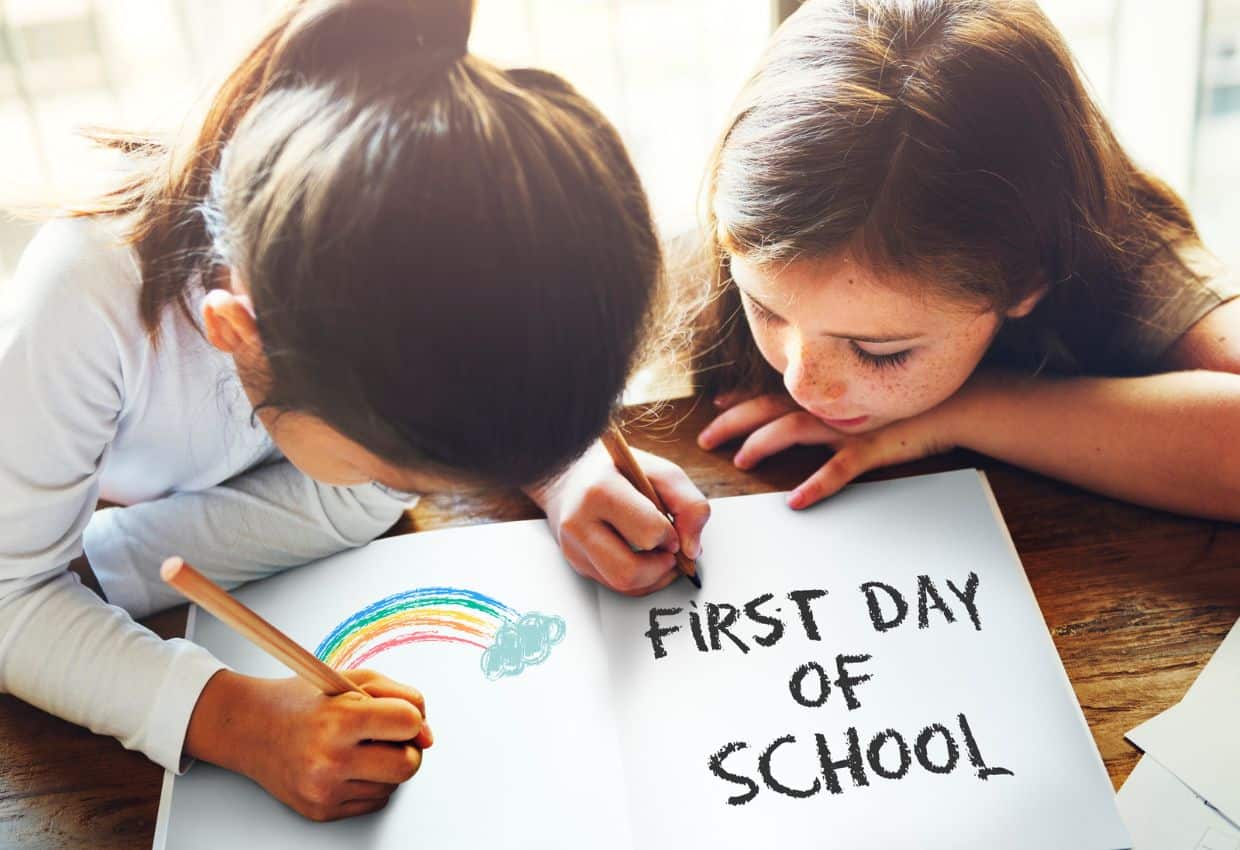Two girls colring a first day of school activity sheet.