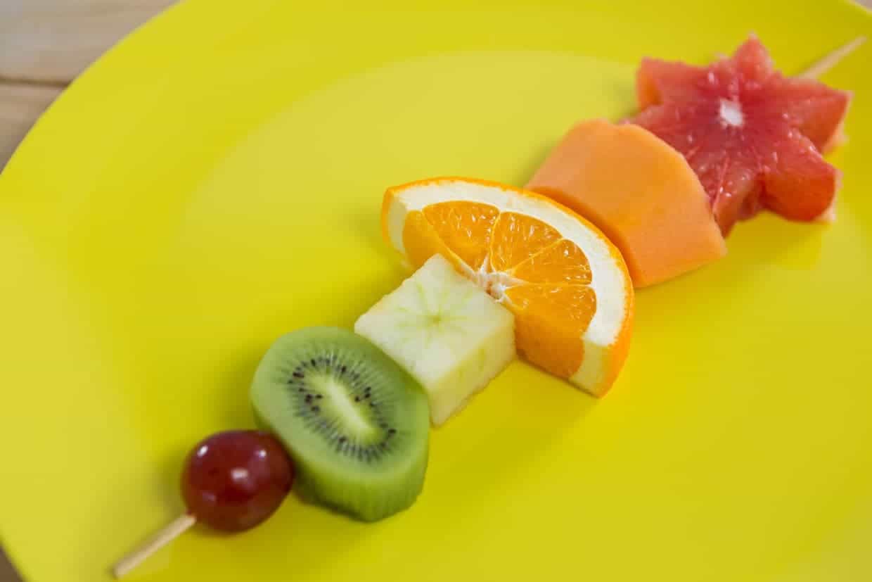 Close up of a fruit skewer on a yellow plate.
