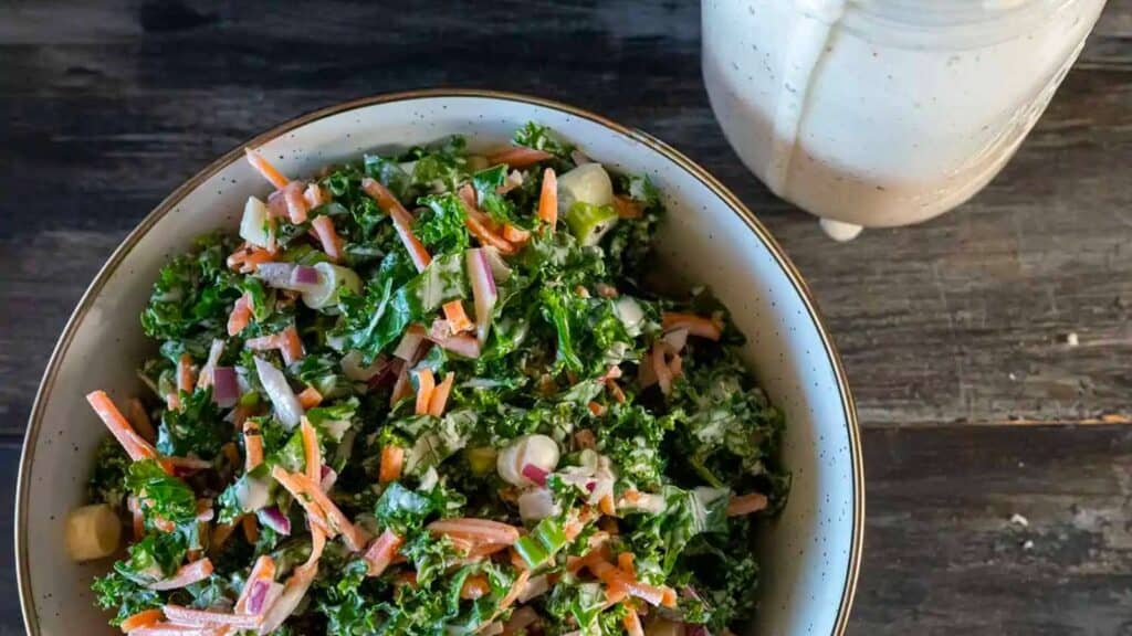 Bowl of kale slaw next to jar of Alabama white sauce.