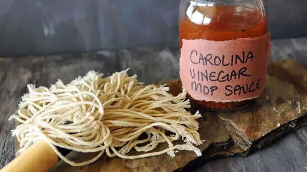 Jar of Carolina vinegar mop sauce next to BBQ mop.