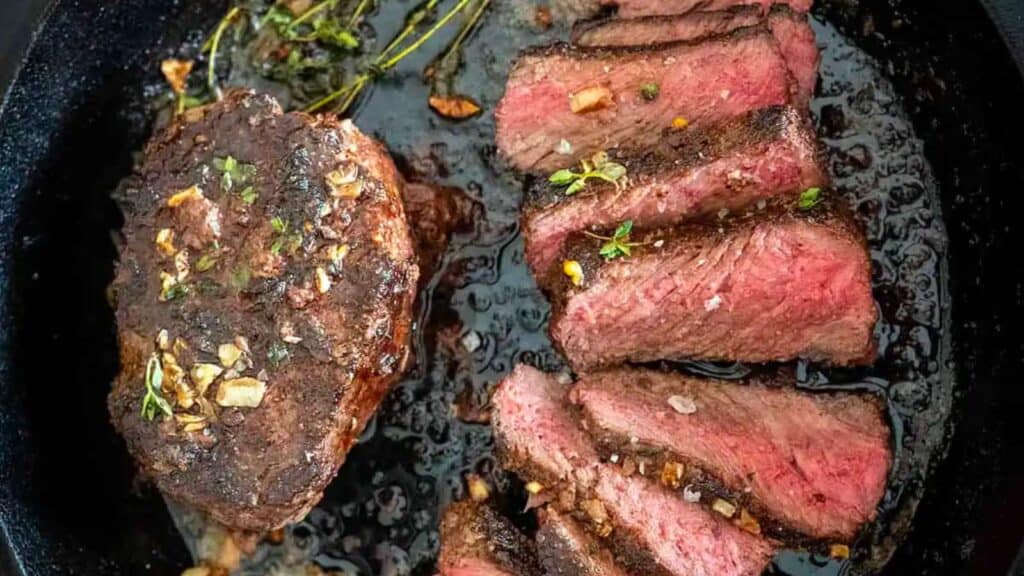 Sliced steak in a cast iron skillet.