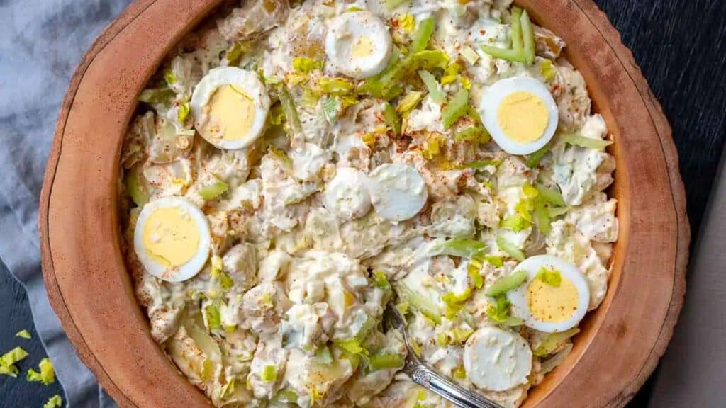 Bowl of classic potato salad with sliced hard-boiled eggs.