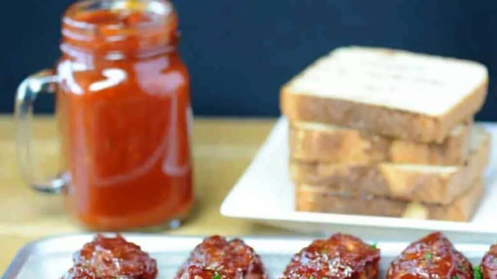 Jar of Whiskey BBQ sauce next to meatballs and bread.