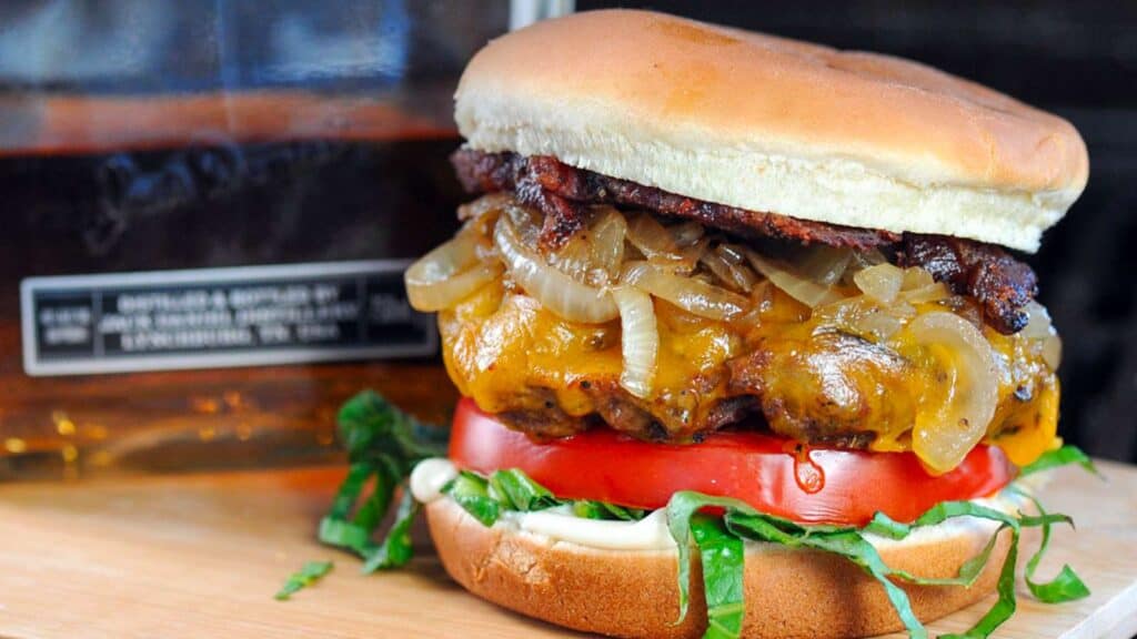 Burger stacked with lettuce, tomato, whiskey onions and beef bacon.