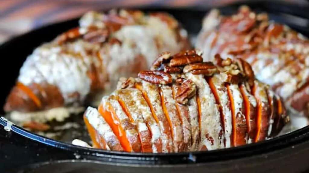 Hasselback sweet potatoes topped with marshmallow and pecans.