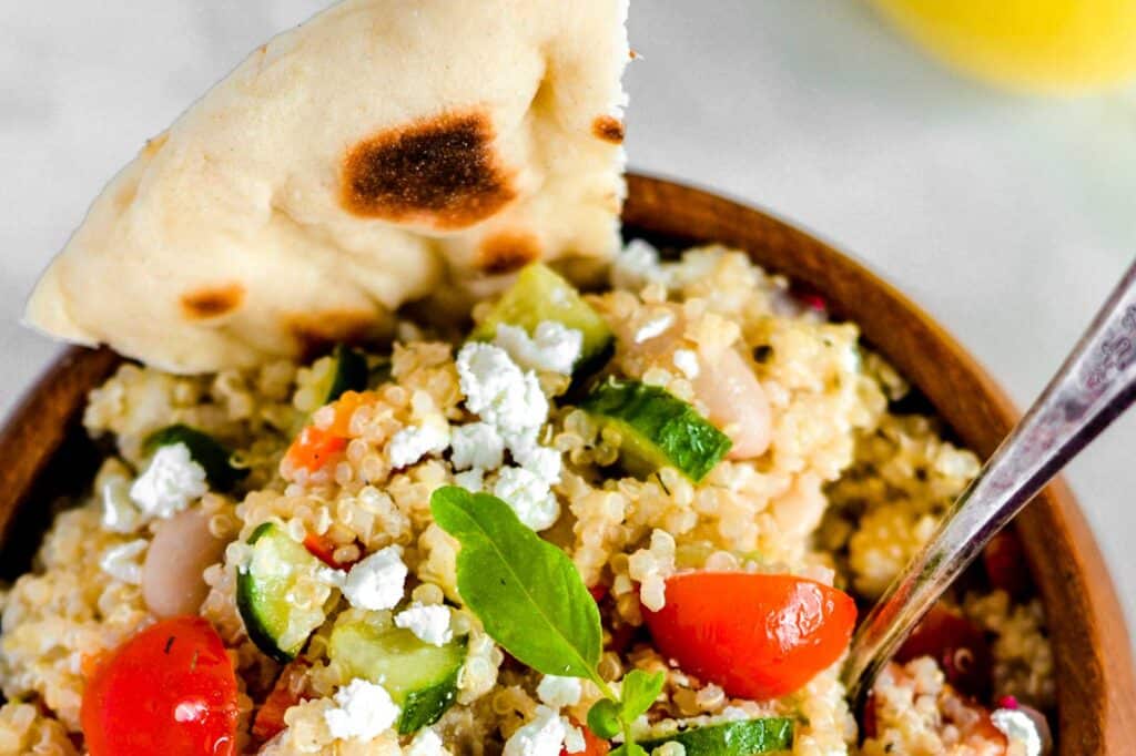 Quinoa salad in a brown bowl, garnished with pita bread