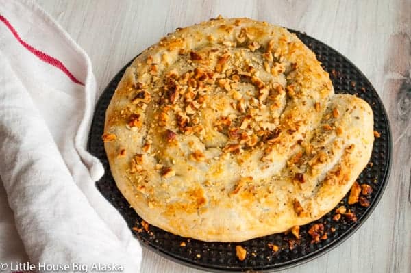 Spanakopita Pie on a plate with a dishtowel next to it.