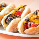 Sausage and peppers sandwiches on a white platter.