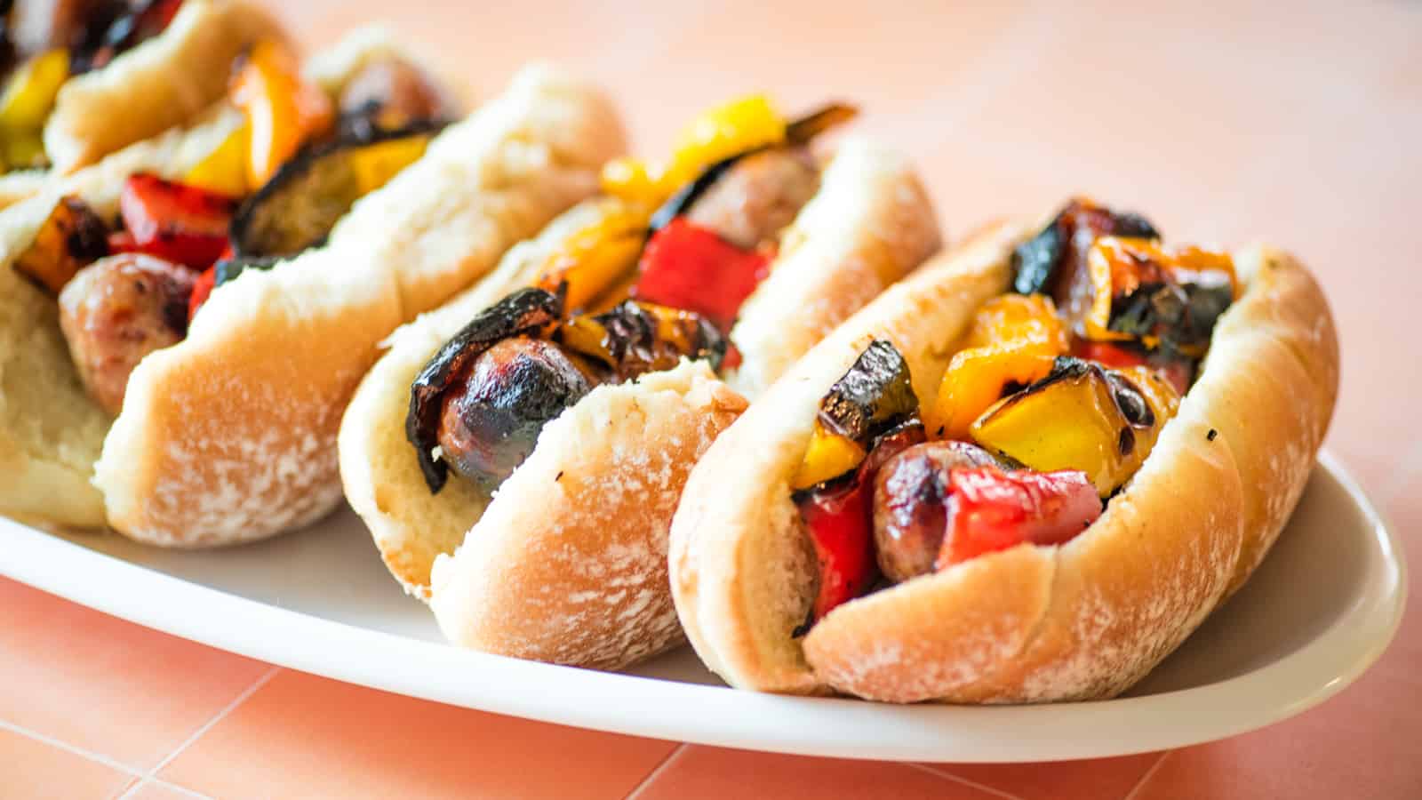 Sausage and peppers sandwiches on a white platter.