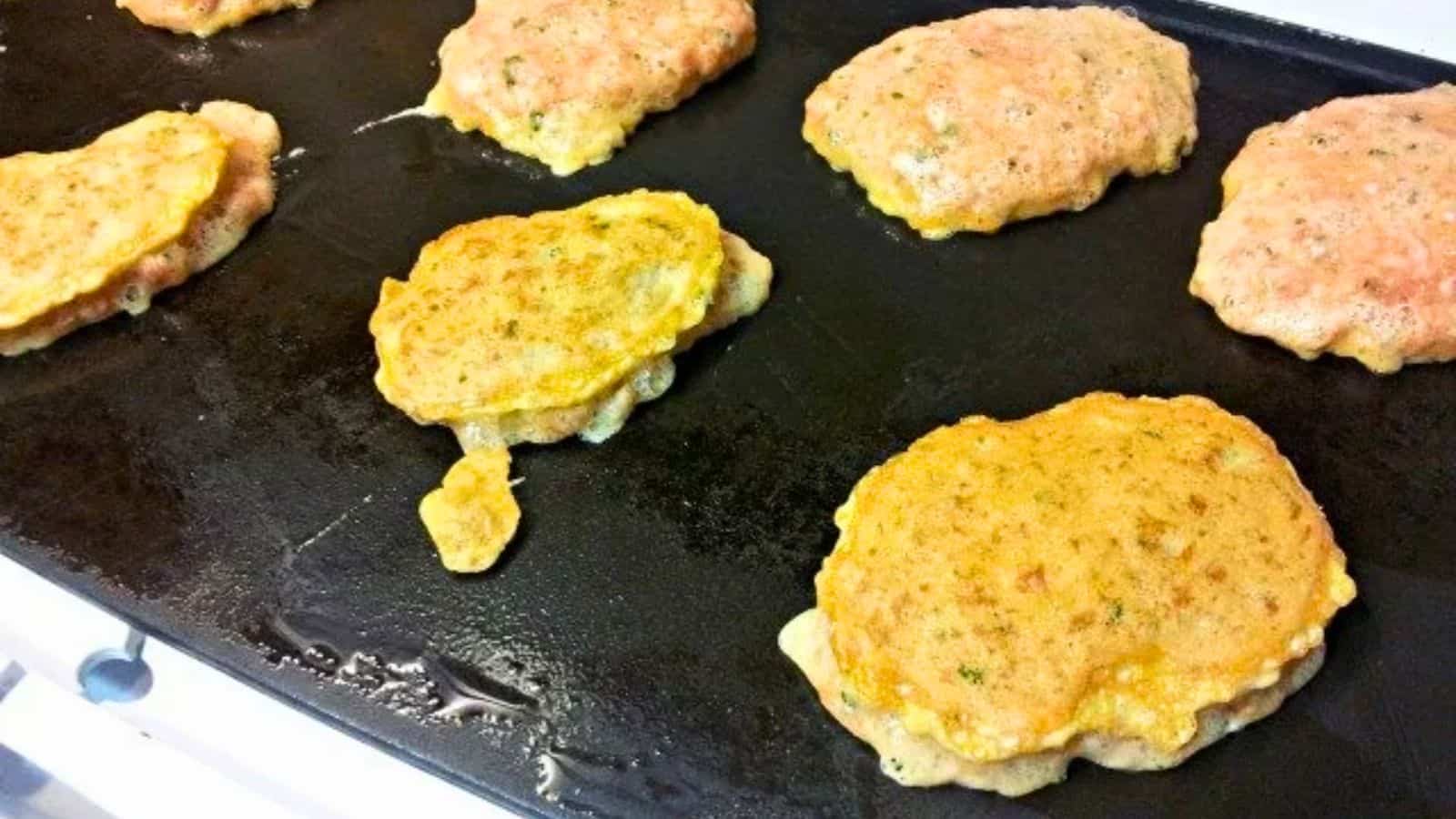 Image shows Ground Turkey Pancakes cooking on a griddle.