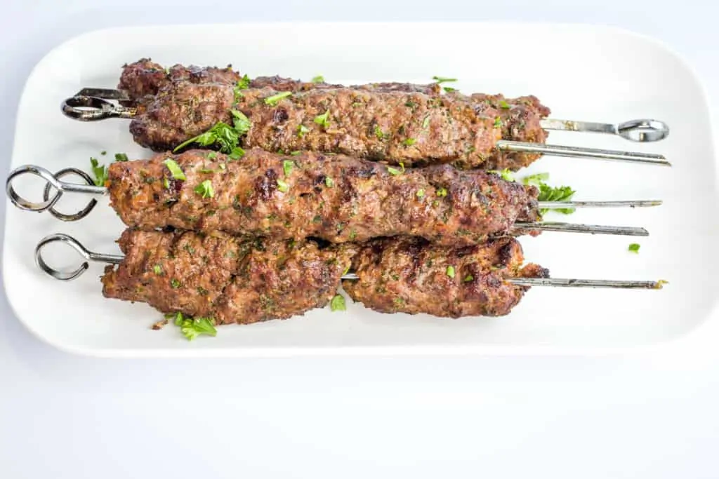 Kefta Beef Kabobs stacked on a white platter.