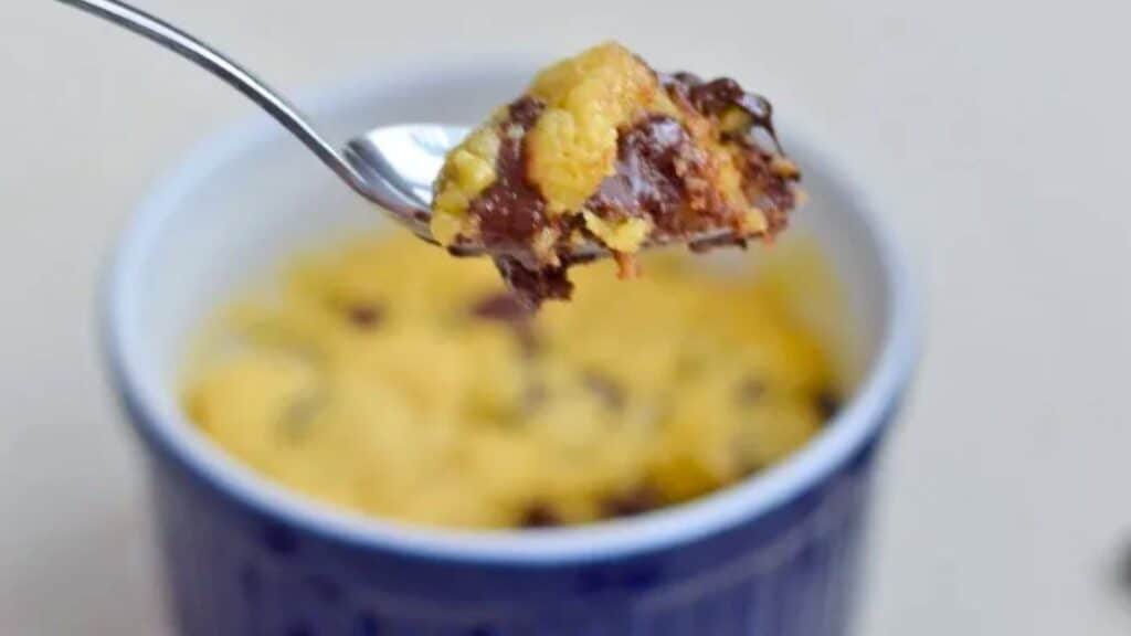 Image shows a close up of a spoon holding a bite of an Individual Chocolate Chip Cookie with the full cookie in the ramekin behind it.