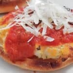 Image shows a close up of a Lasagna Pizza Appetizer topped with freshly grated parmesan sitting on a white plate with another one in the background.