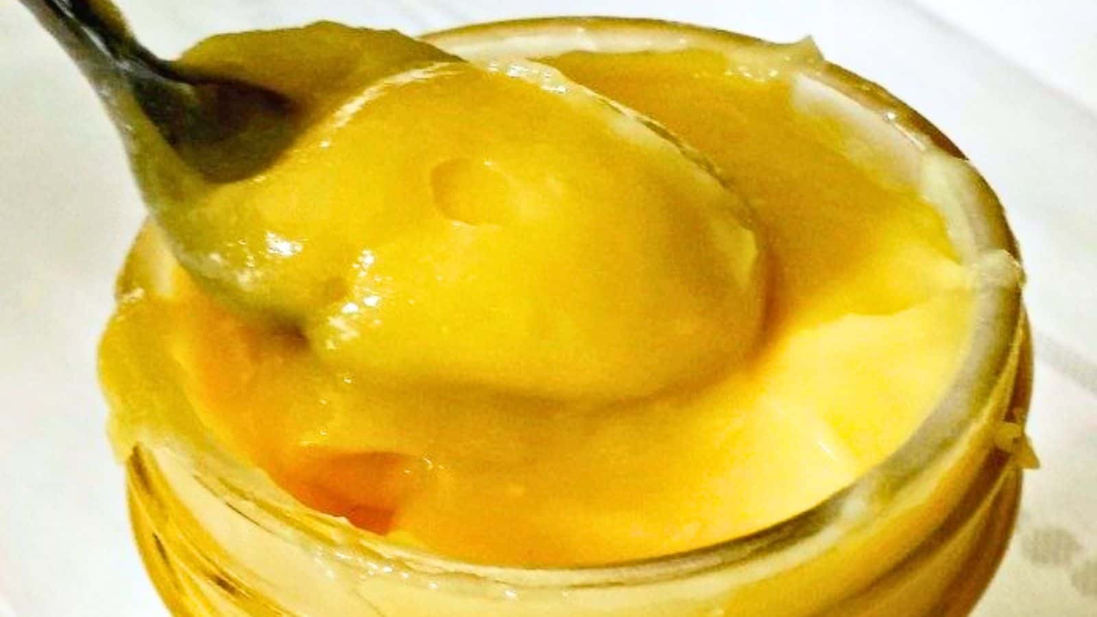 Image shows a spoon dipping into a jar of Lemon Curd.