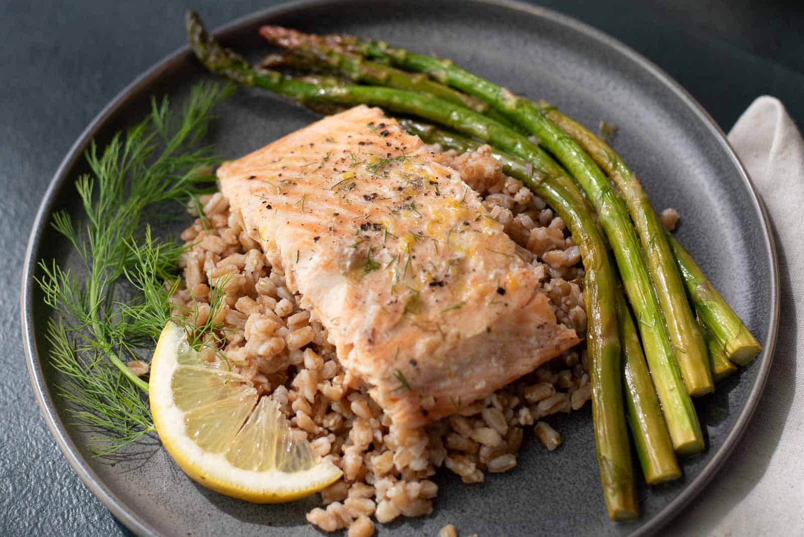 Hands holding a baking dish with Lemon Dill Salmon and Asparagus.