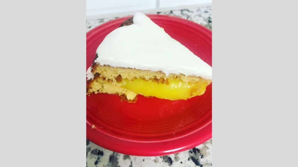 Slice of lemon gold cake on red plate.