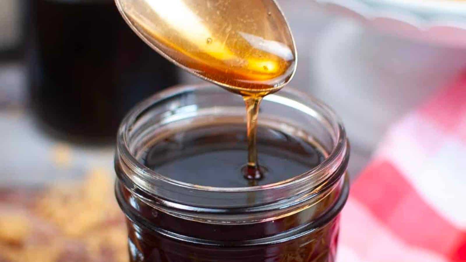 Pancake syrup dripping from spoon to jar.