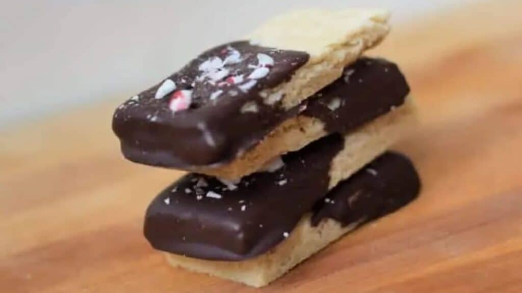 Image shows a stack of four Peppermint Shortbread Cookies on a wooden table.