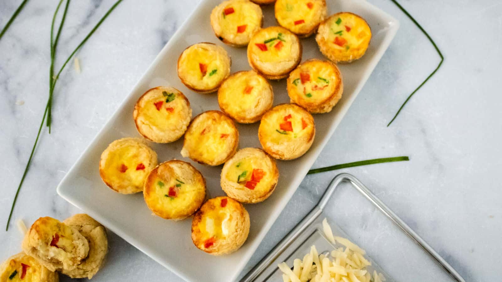 Mini Swiss cheese quiches on a white platter.