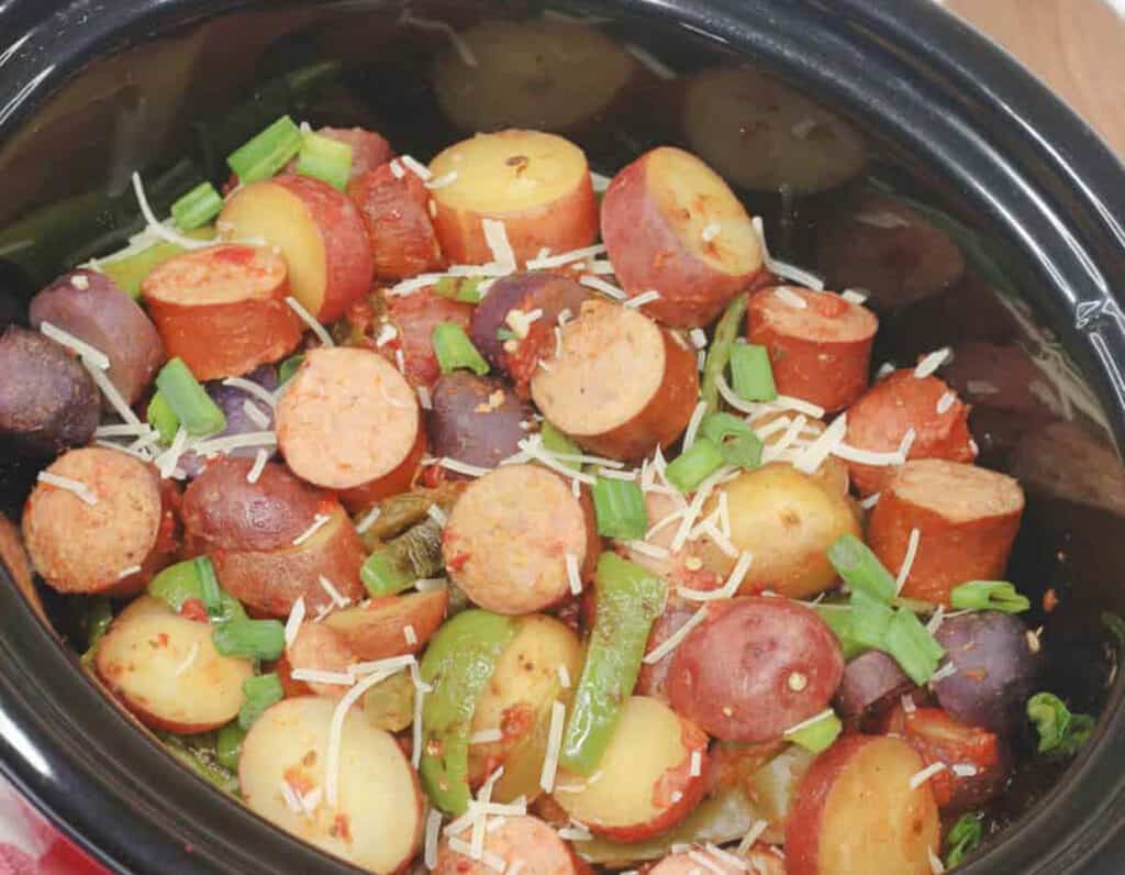 Sausage and potatoes in a crock pot with peppers. 