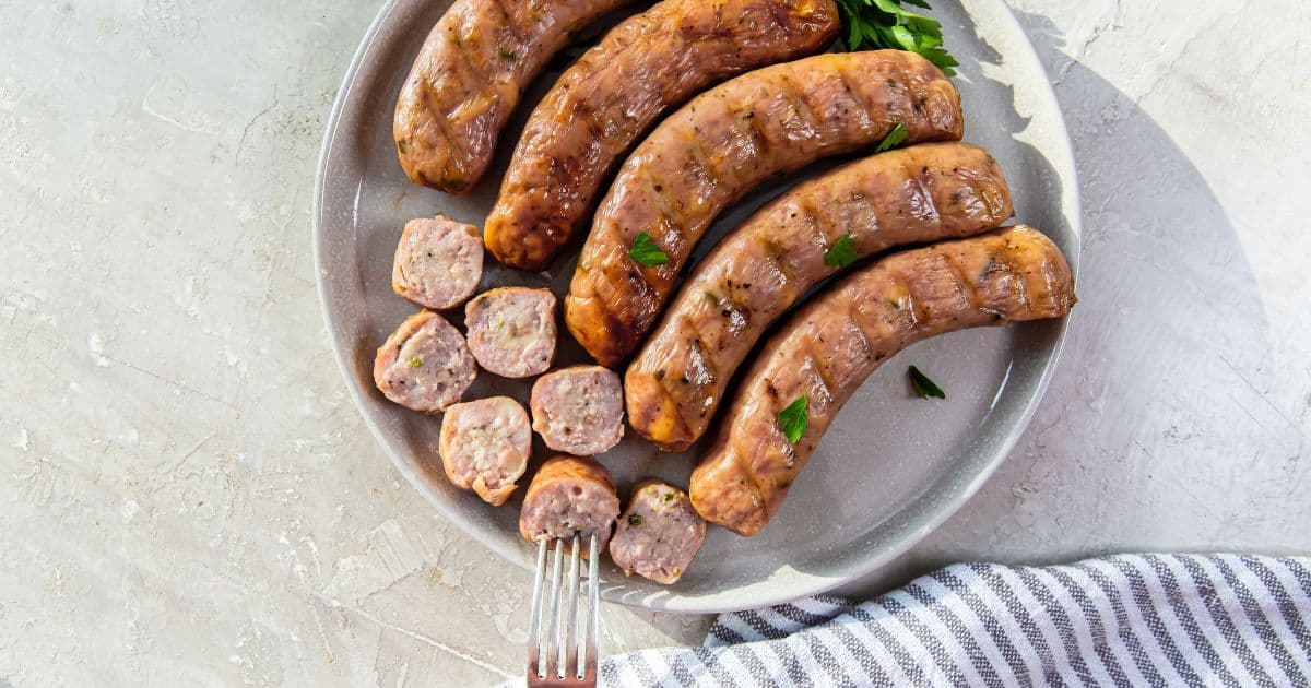 Smoked brats on a grey platter with some sliced.