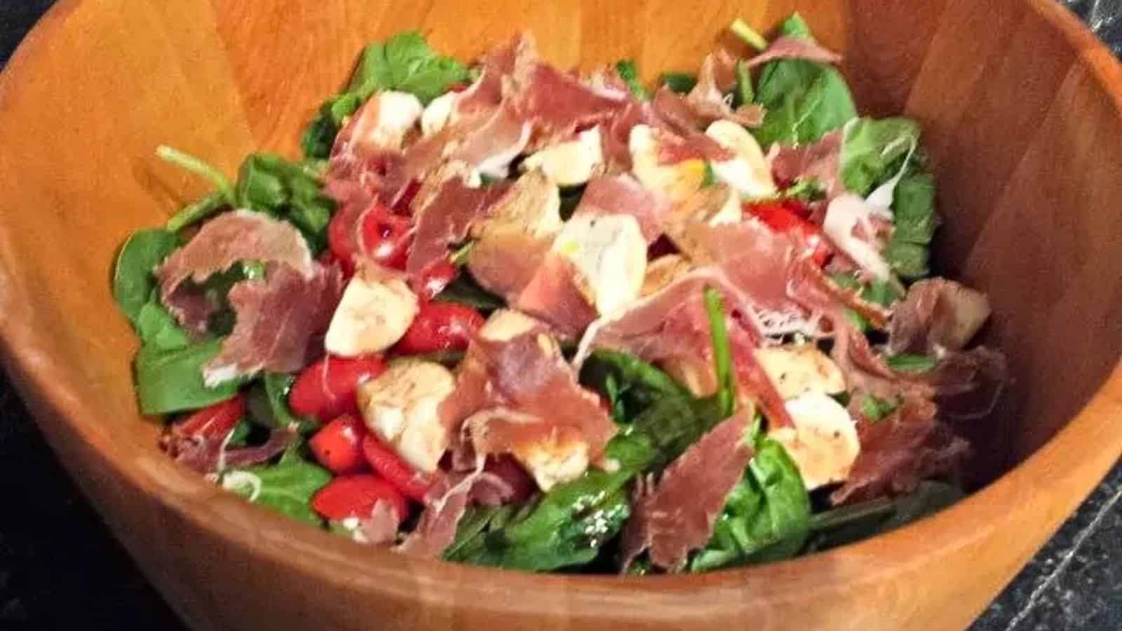 Image shows a Spinach Caprese Salad in a wooden salad bowl.