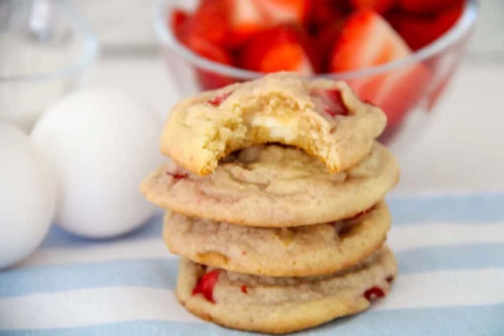 Stack of strawberry cheesecake cookies with bite taken out of top one.