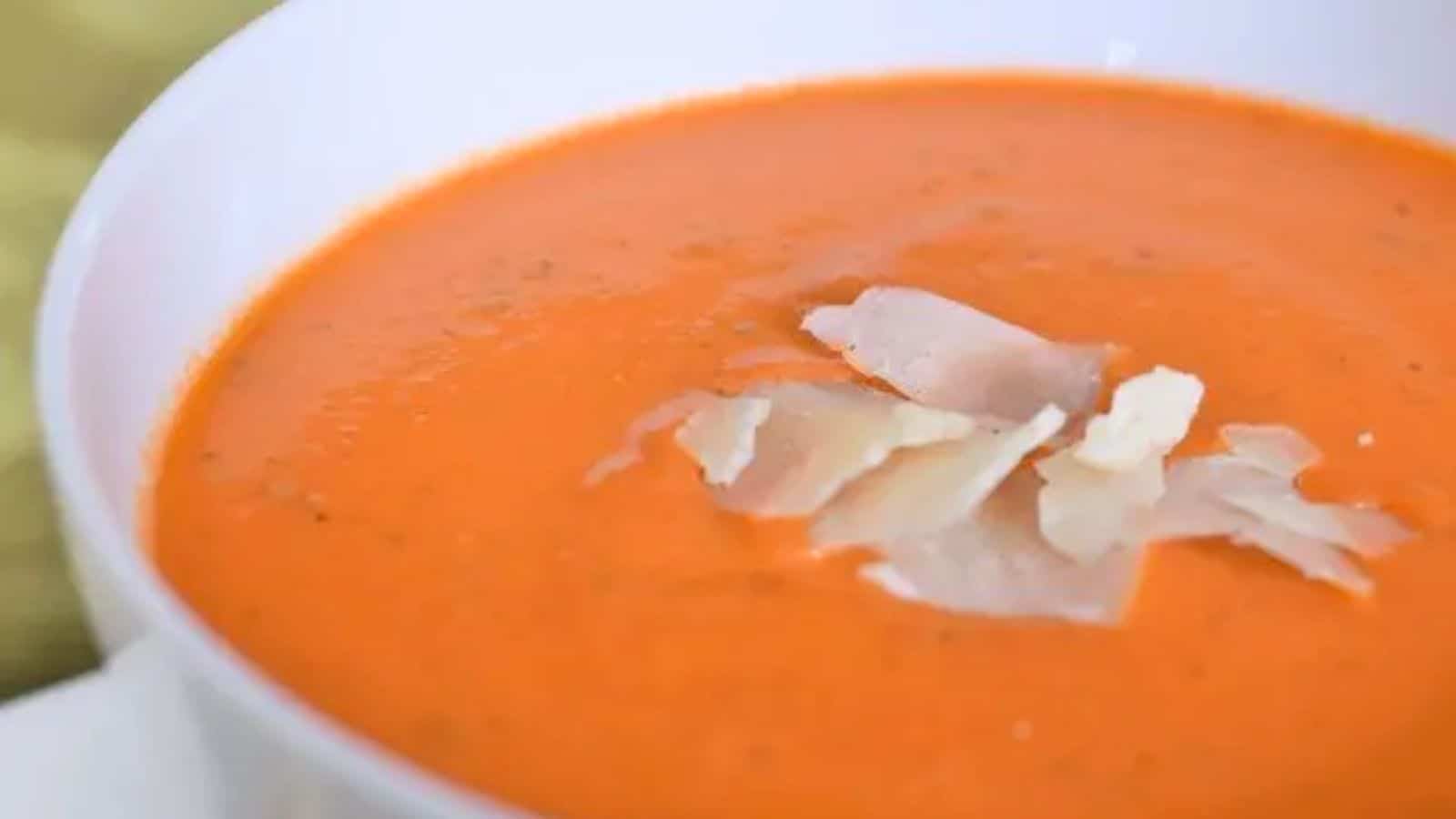 Image shows a close up of a bowl of Tomato Basil Bisque with grated parmesan on top of it.