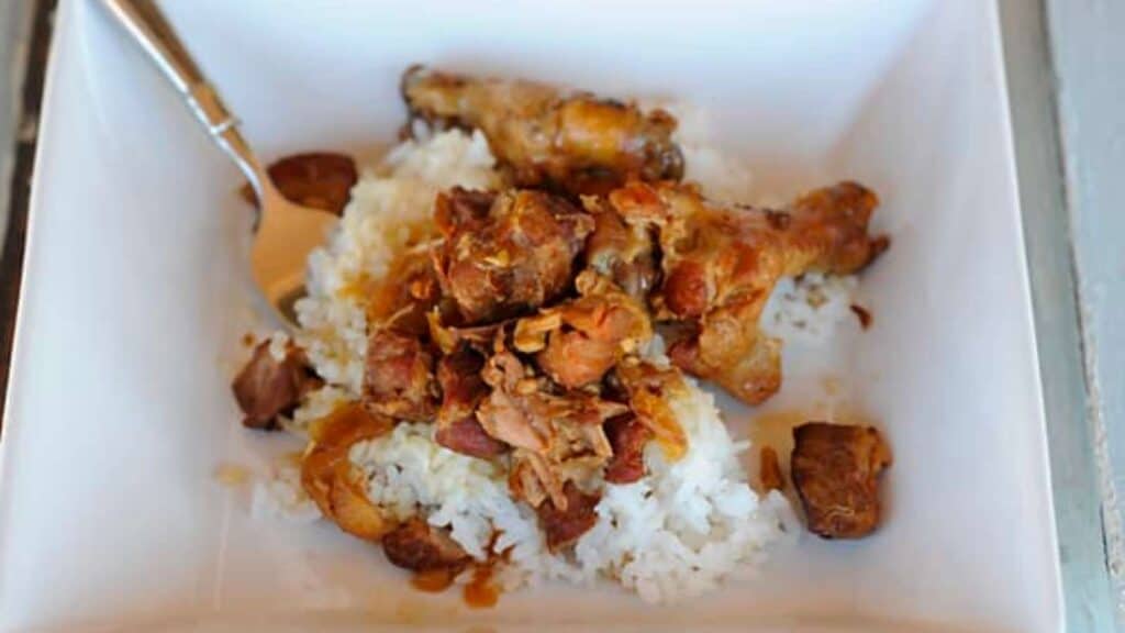 Bowl of chicken and pork adobo over white rice.