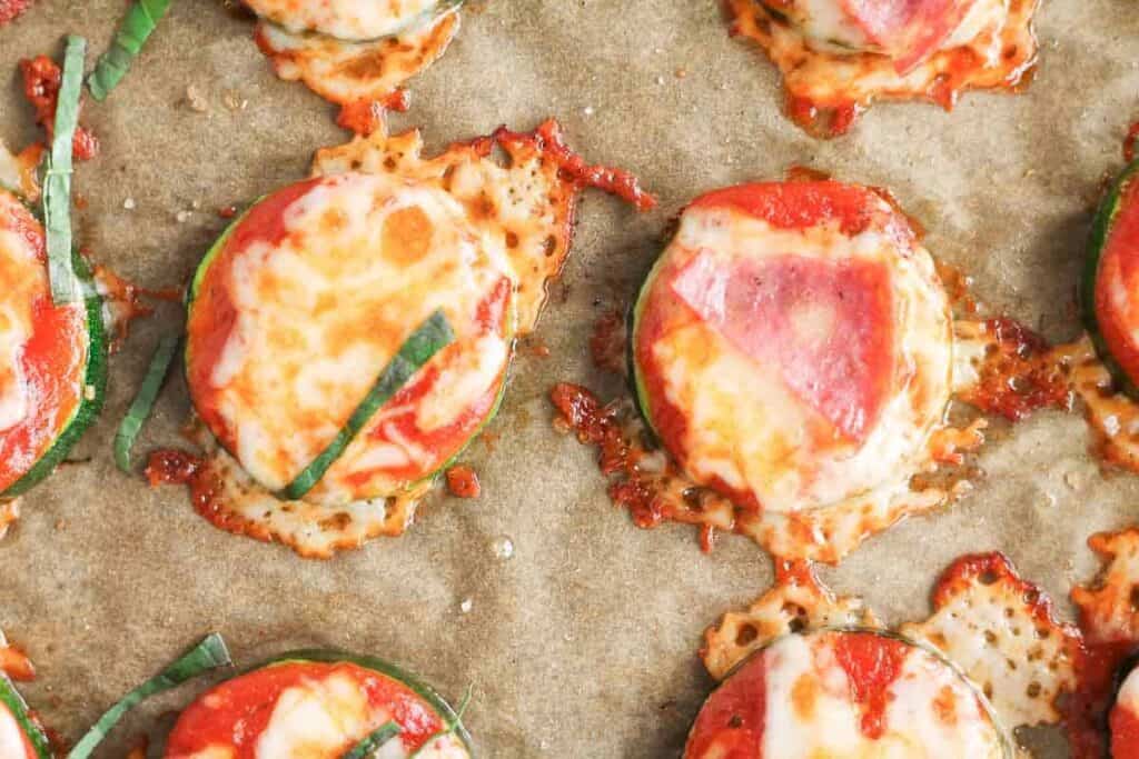 Overhead image of mini zucchini pizzas topped with bubbling cheese.