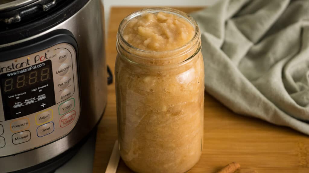 Mason jar with instant pot applesauce next to a green napkin.