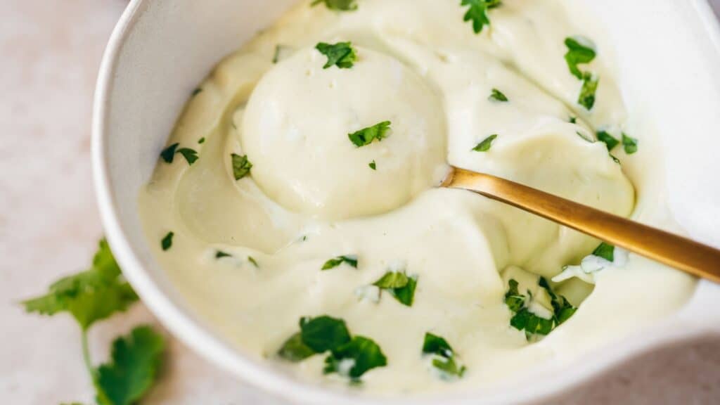 Close shot of a golden spoon scooping avocado cream from a small bowl.