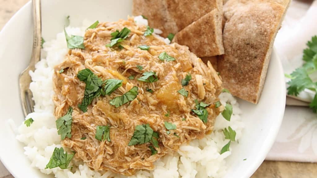 BBQ peach pulled chicken over rice with pita bread in a bowl.